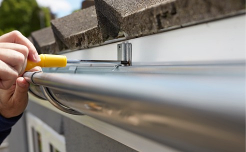 close-up-of-man-replacing-guttering-on-exterior-of-house