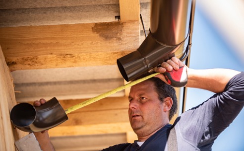 roofer-builder-worker-finishing-folding-a-metal-gutter-