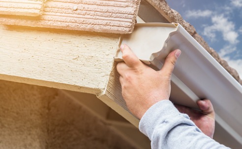 worker-attaching-aluminum-rain-gutter-to-fascia-of-house-picture-id648964160
