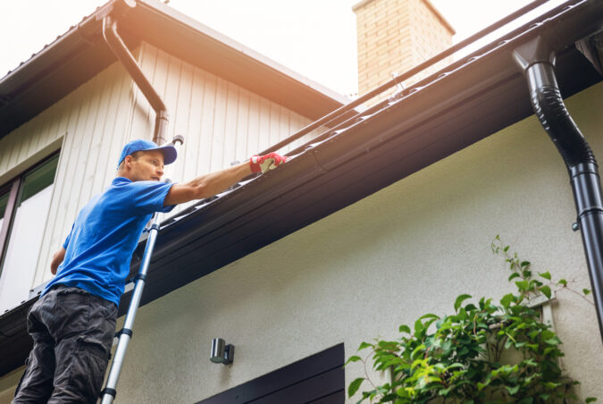 A member of Peoria Gutter Masters performs gutter cleaning on a home
